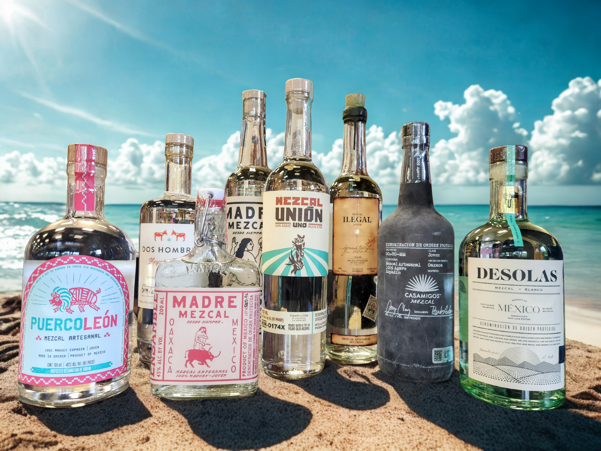 Bottles of mezcal sit on a beach in Mexico
