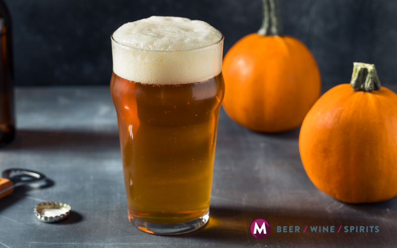 Glass of pumpkin beer with foam head surrounded by fresh pumpkins – Mulberry Max September specials beer selection